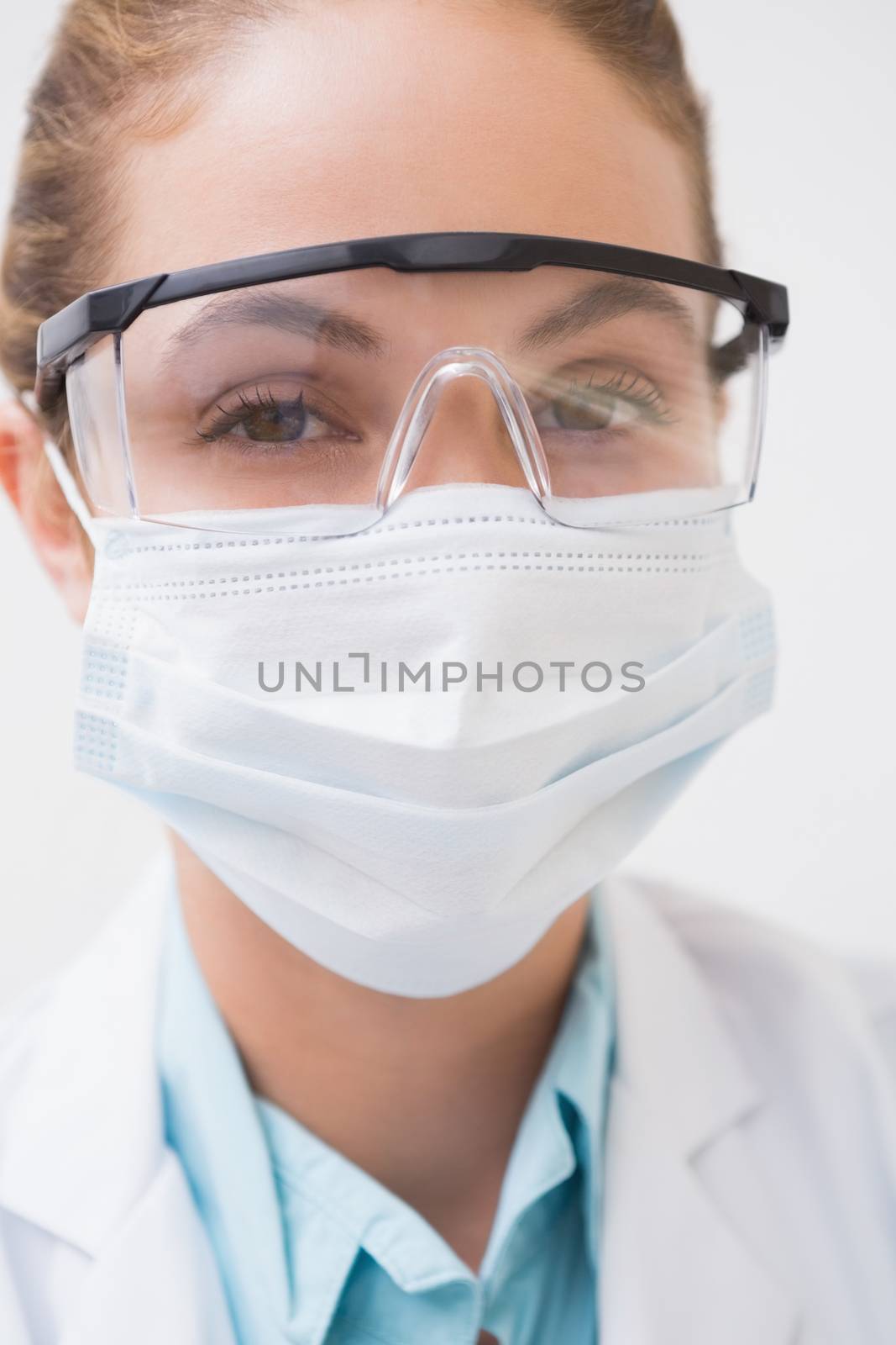 Dentist with surgical mask and protective glasses by Wavebreakmedia