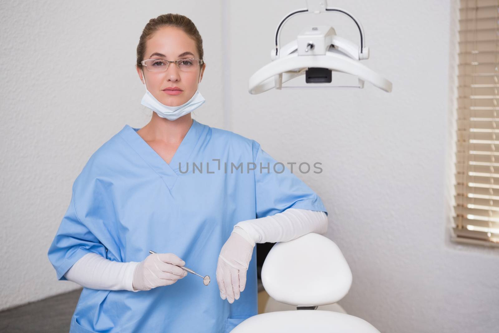 Dentist in blue scrubs looking at camera  by Wavebreakmedia
