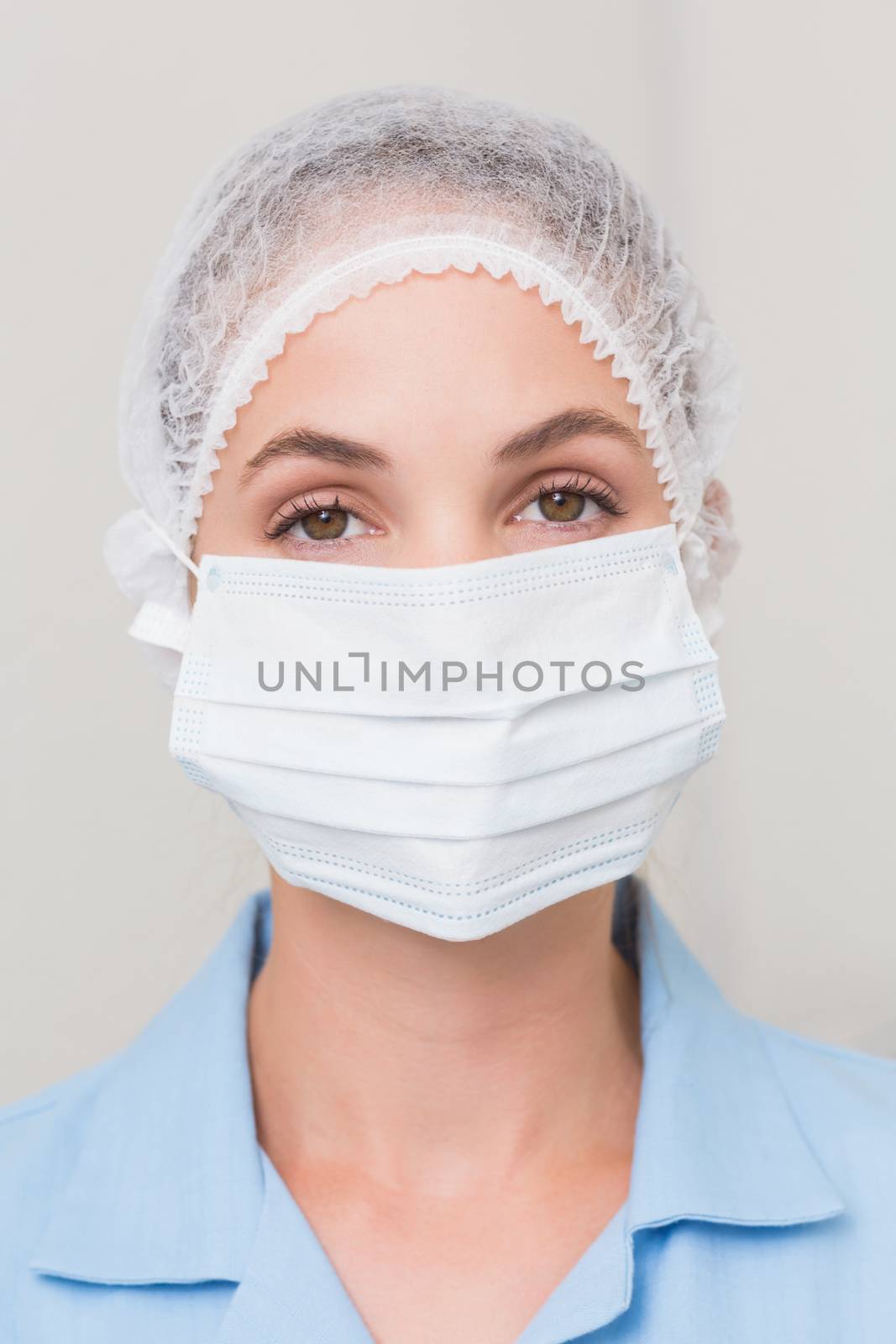 Dentist in surgical mask and cap looking at camera by Wavebreakmedia
