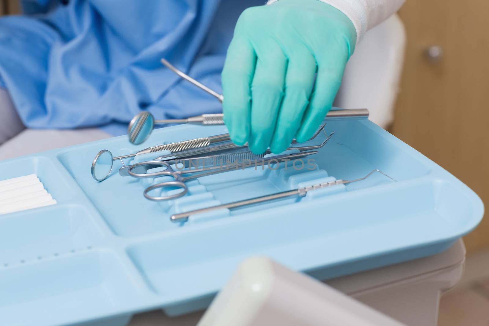 Dentist in blue scrubs picking up tools by Wavebreakmedia