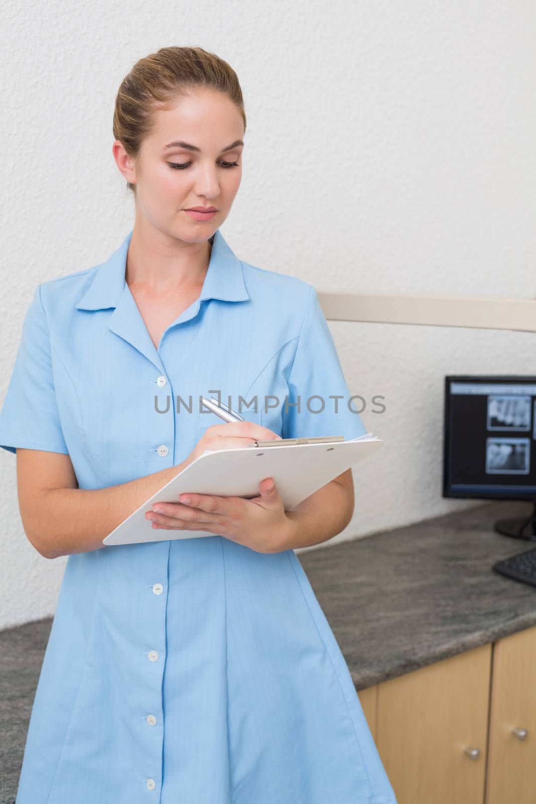 Dental assistant writing in clipboard at the dental clinic