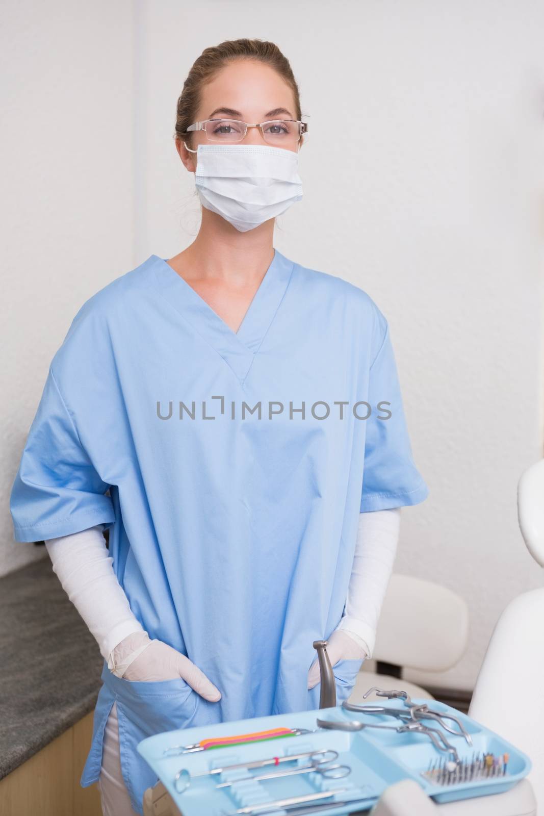 Dentist in blue scrubs looking at camera in mask at the dental clinic