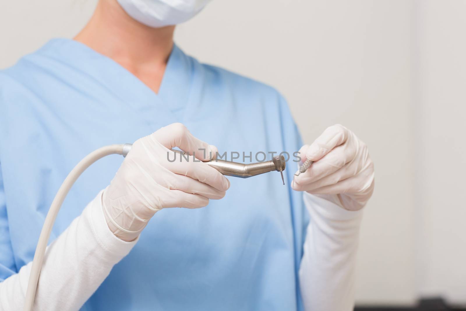 Dentist in blue scrubs holding drill  by Wavebreakmedia