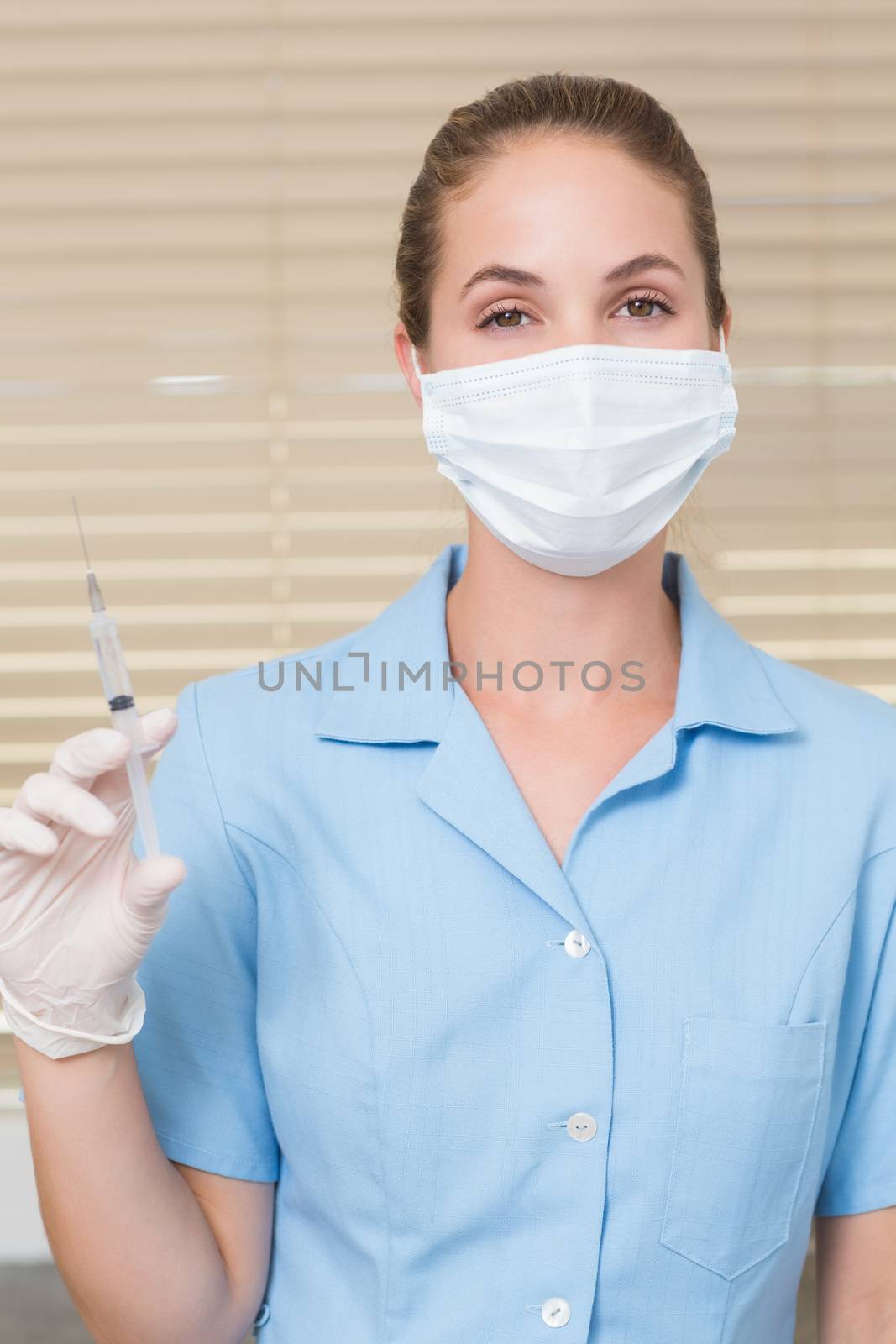 Dental assistant holding injection looking at camera by Wavebreakmedia