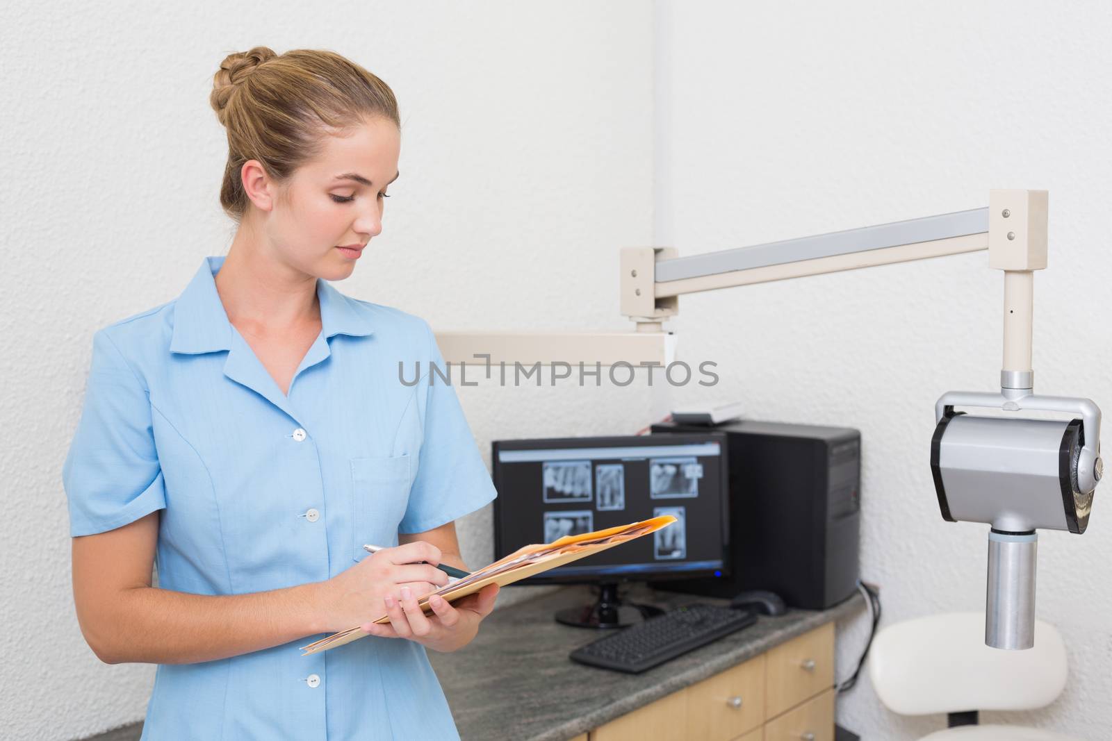 Dental assistant writing in folder at the dental clinic