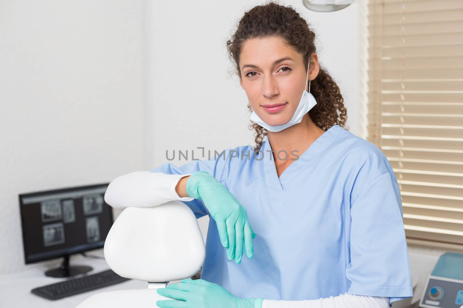 Dentist in blue scrubs smiling at camera at the dental clinic