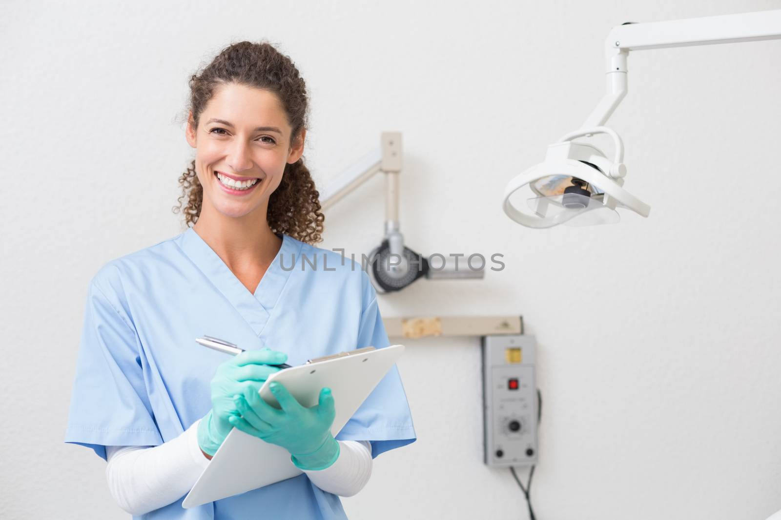 Dentist in blue scrubs writing on clipboard at the dental clinic