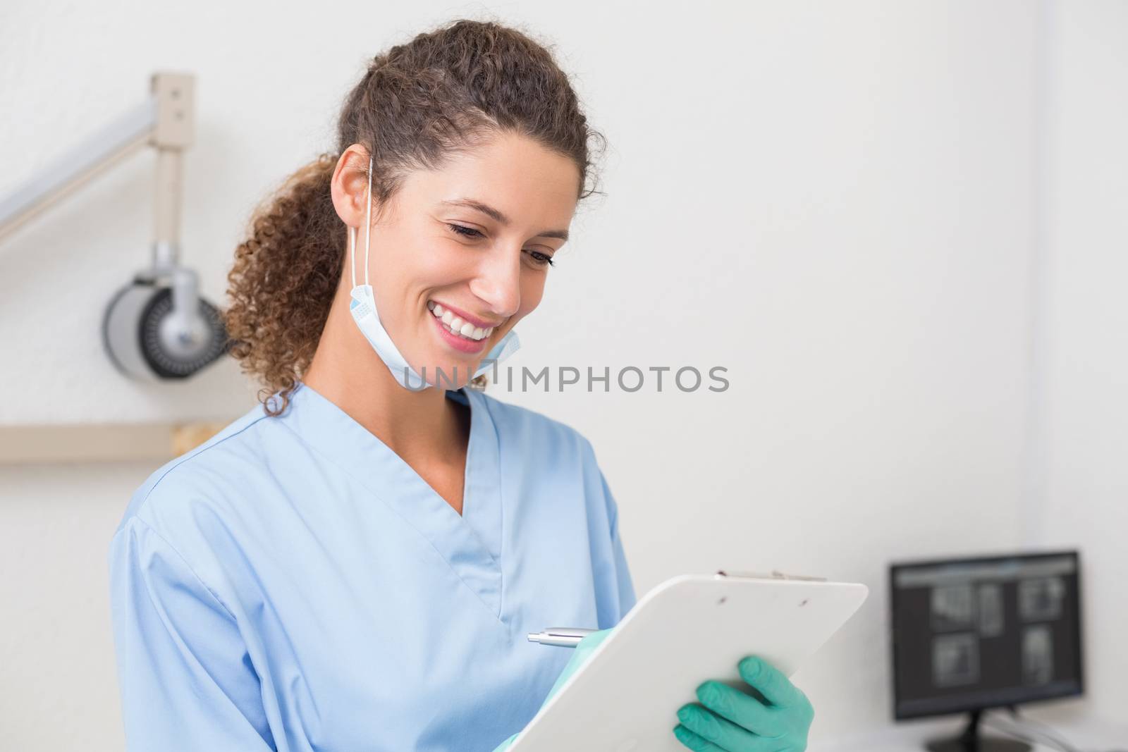 Dentist in blue scrubs writing on clipboard at the dental clinic