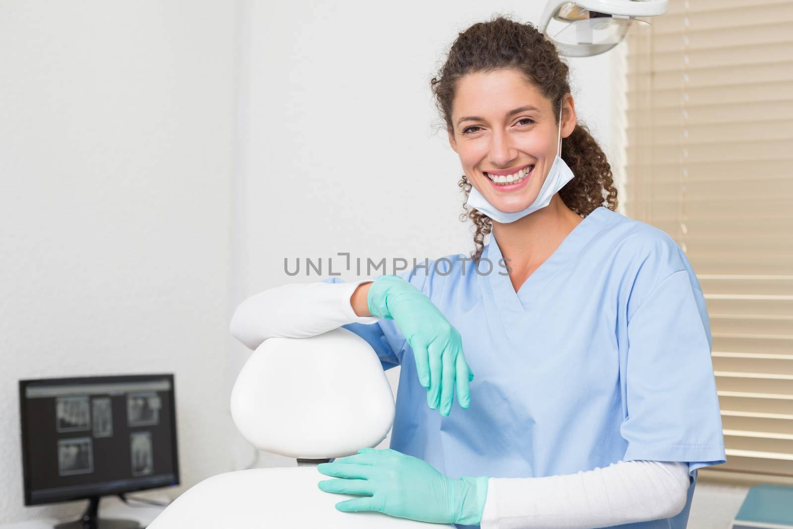 Dentist in blue scrubs smiling at camera at the dental clinic