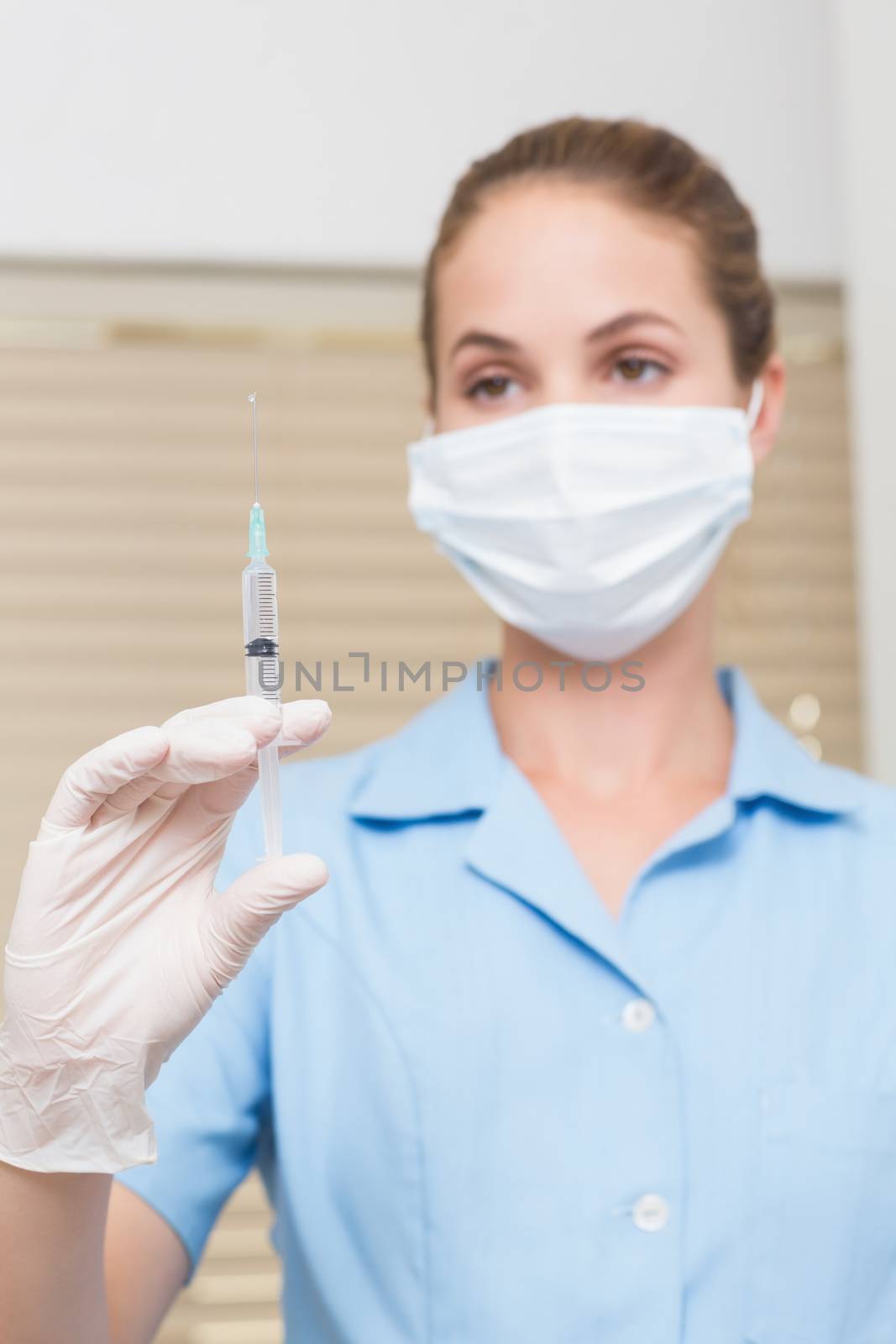 Dental assistant holding injection looking at it by Wavebreakmedia