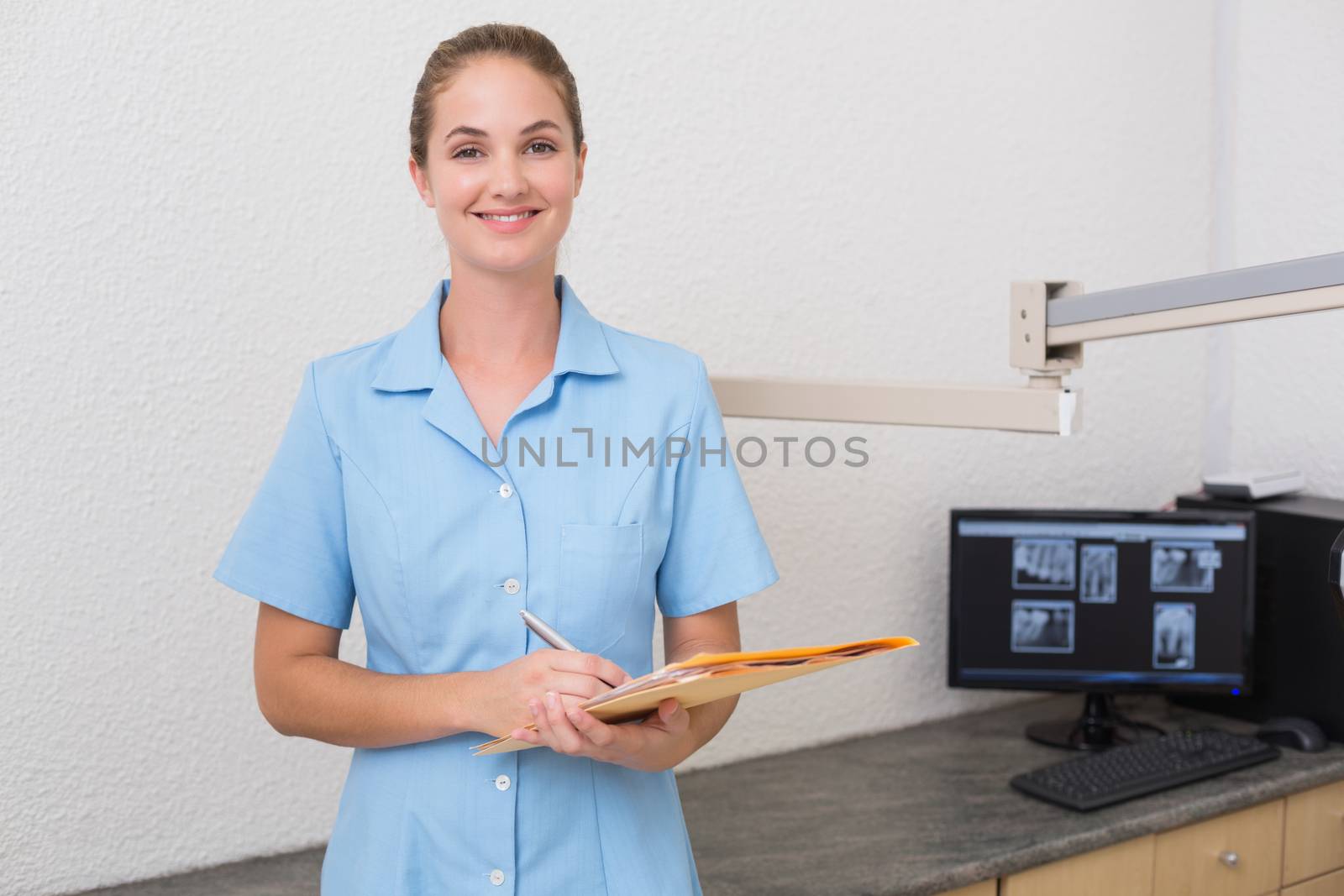 Dental assistant writing in folder at the dental clinic