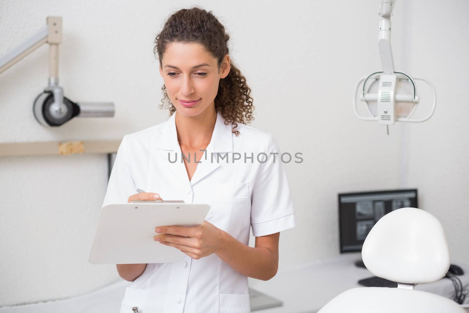 Dental assistant writing in clipboard at the dental clinic