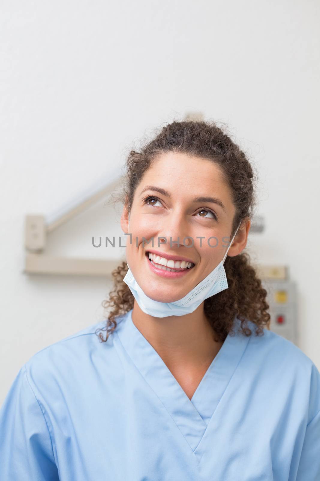 Dentist in blue scrubs smiling and thinking at the dental clinic