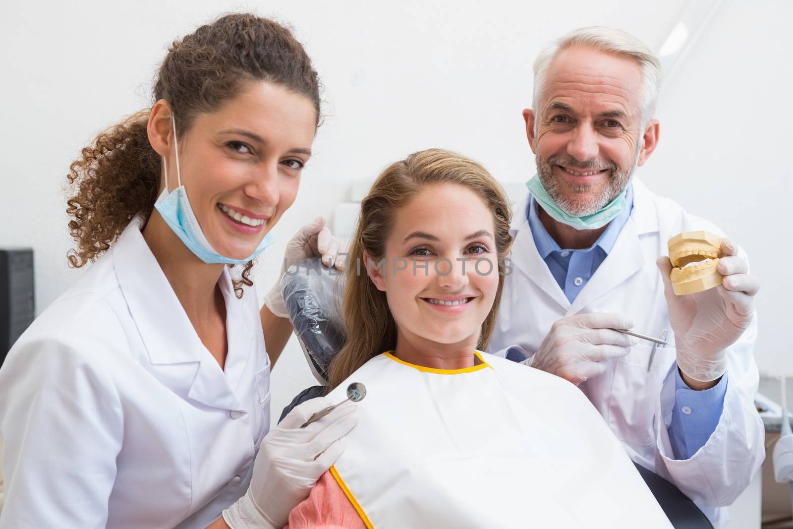 Dentist examining a patients teeth in the dentists chair with assistant by Wavebreakmedia