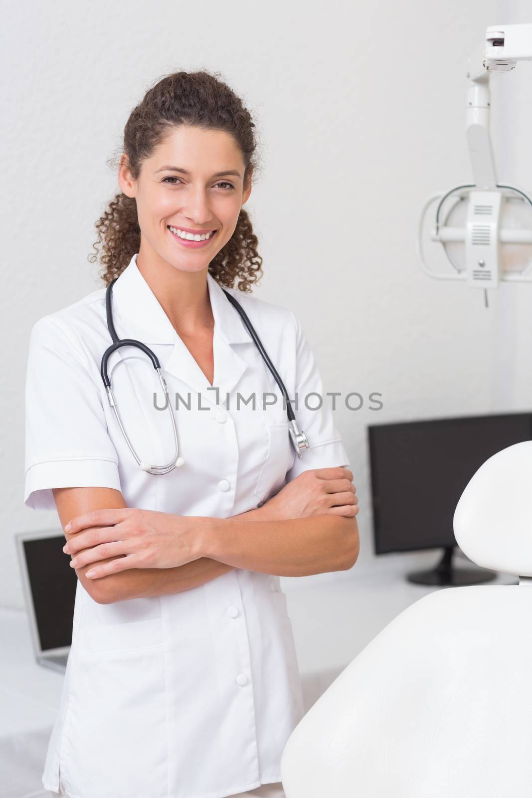 Dental assistant smiling at camera beside chair by Wavebreakmedia
