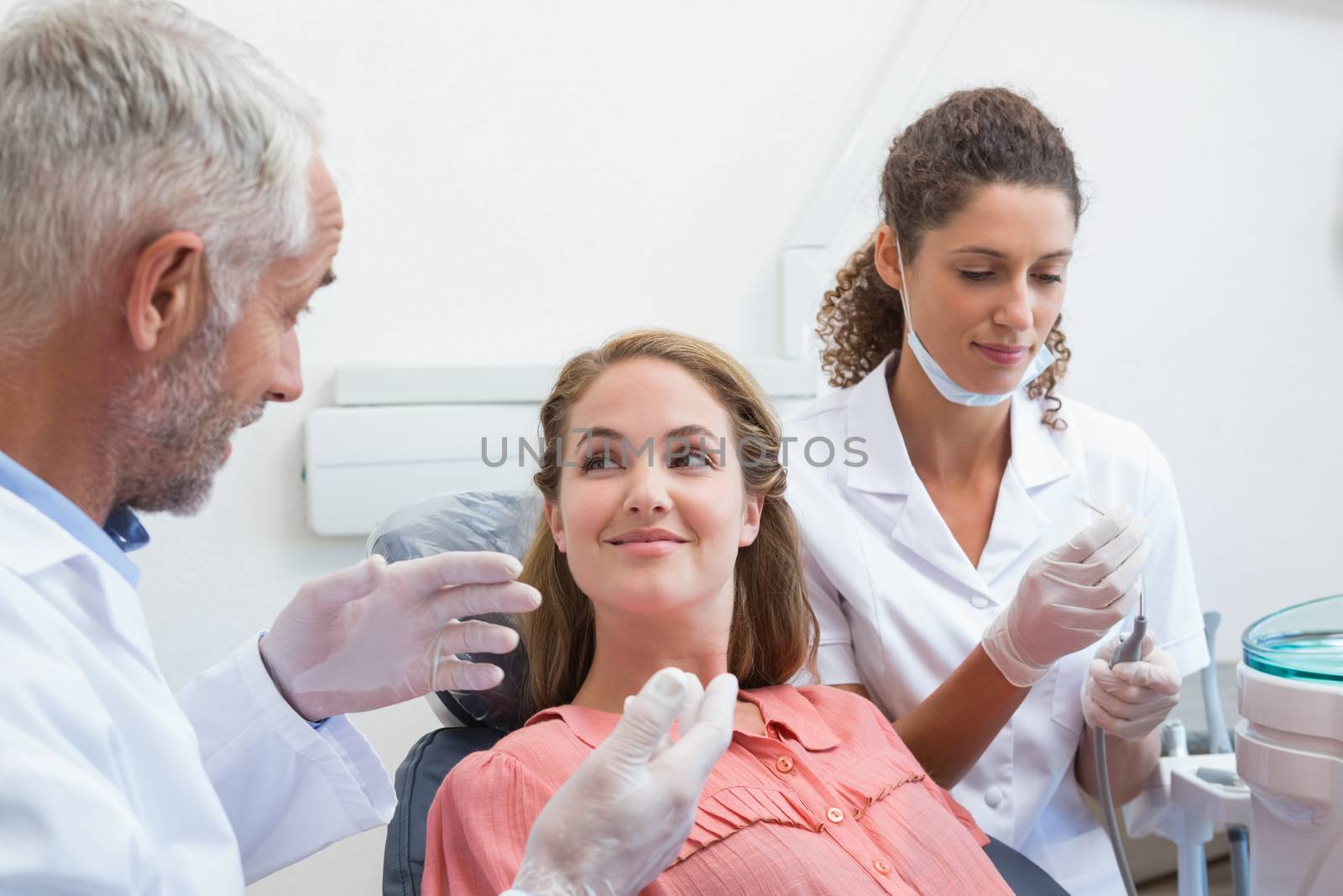 Dentist talking with patient while nurse prepares the tools by Wavebreakmedia