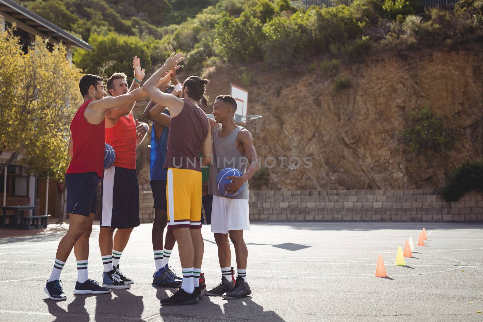 Basketball players giving high five to each other by Wavebreakmedia