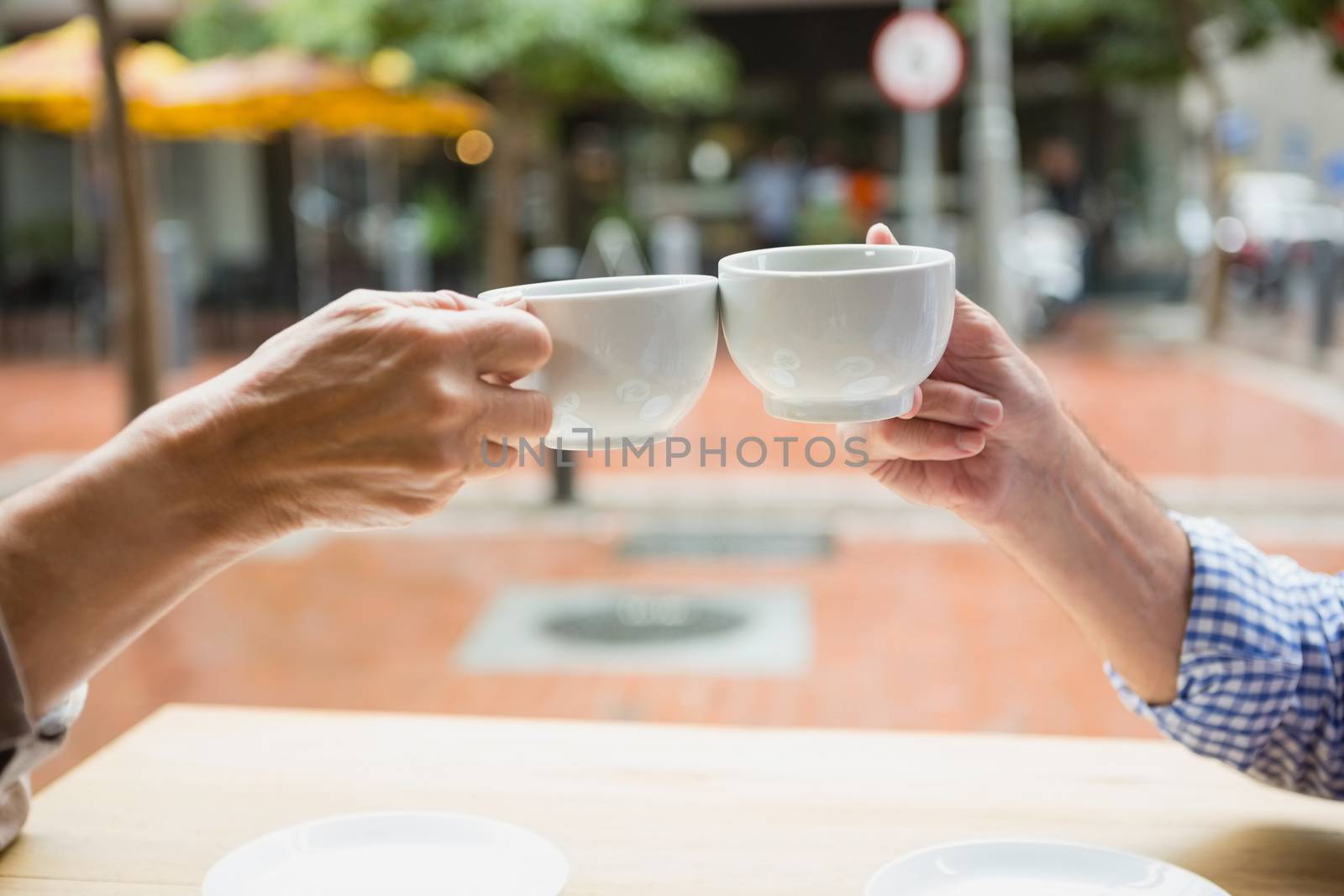 Hands of senior couple toasting coffee cups by Wavebreakmedia