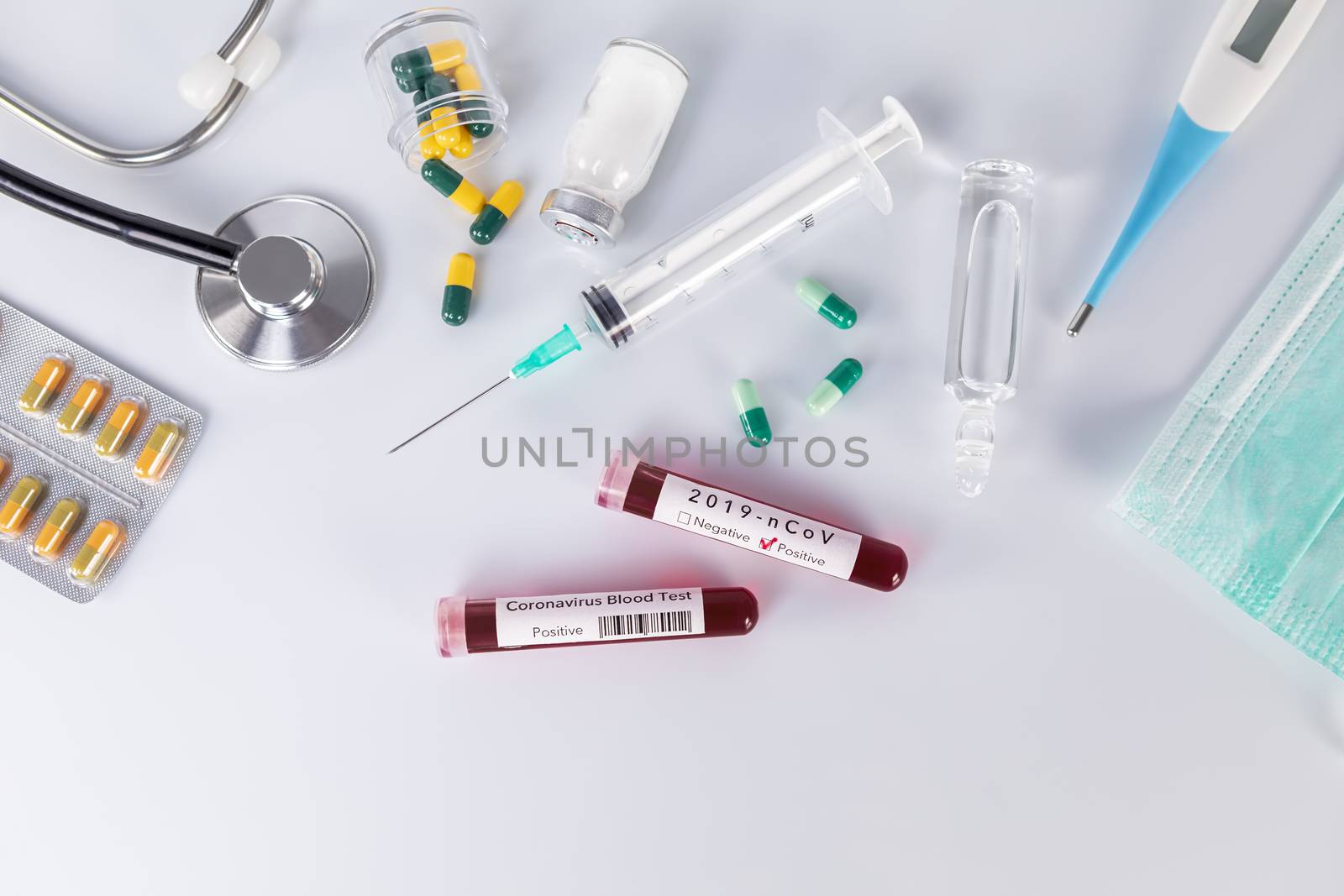 Blood test tube with the Coronavirus disease for virus test and research. Blood test tube with protective masks, medicines, thermometer, stethoscope and syringe on a white background.