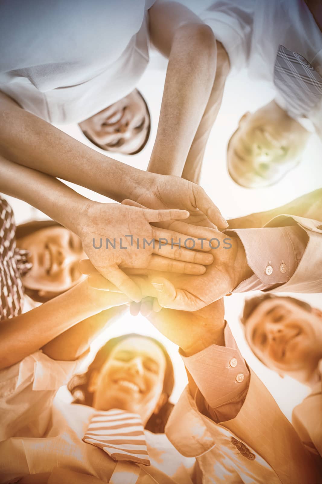 Directly below portrait business people stacking hands while standing in office