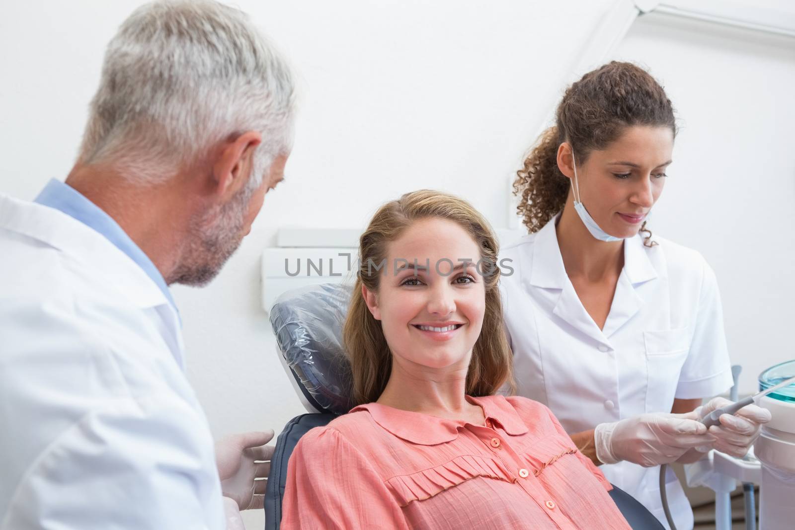 Dentist talking with patient while nurse prepares the tools by Wavebreakmedia