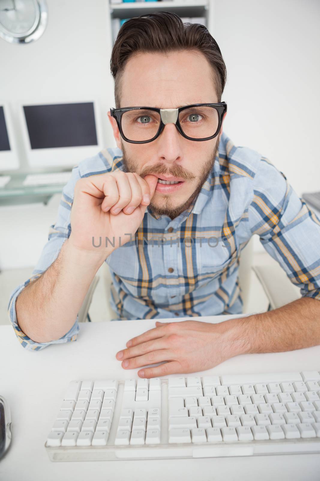 Puzzled nerdy businessman working on computer in his office