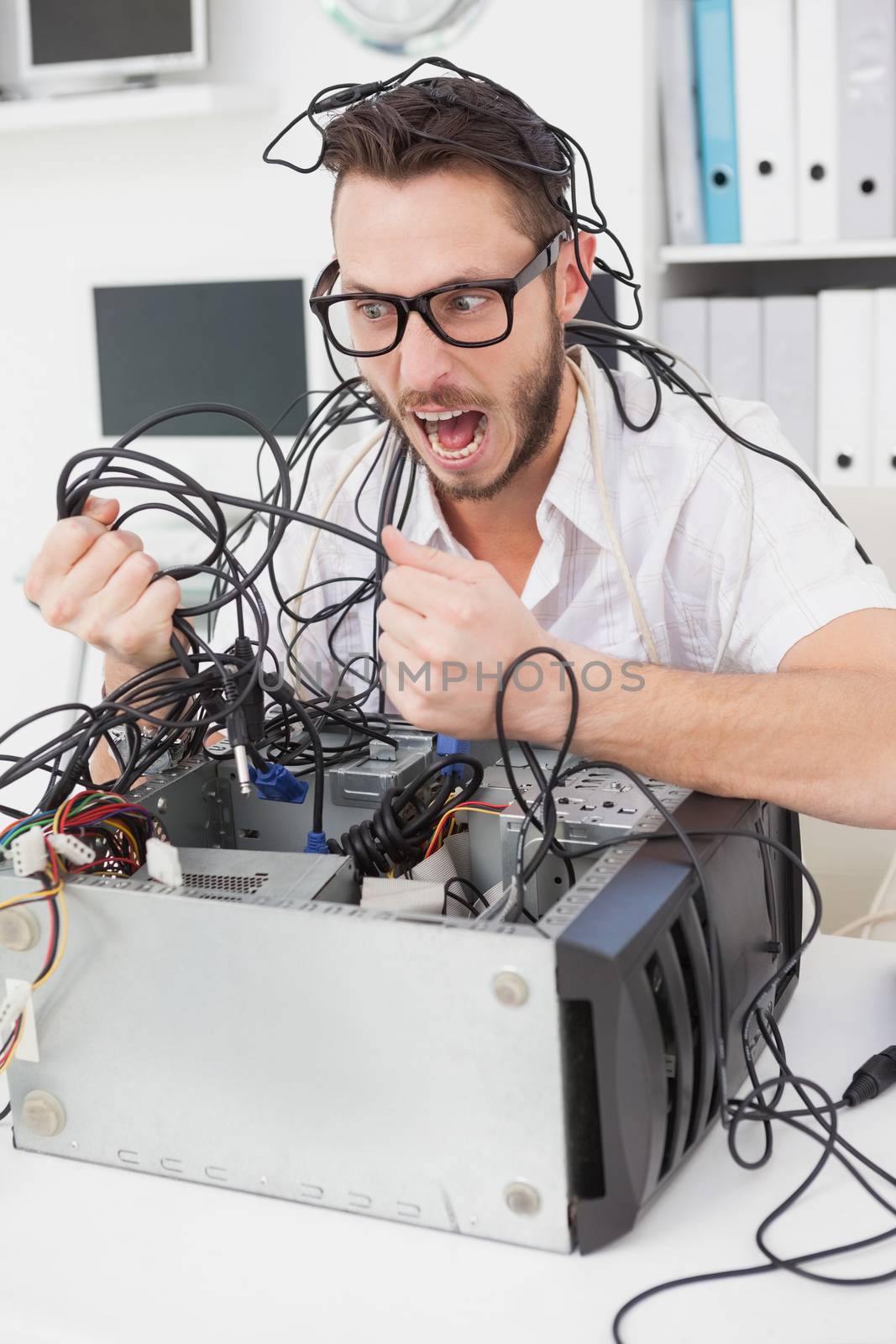 Angry computer engineer pulling wires by Wavebreakmedia