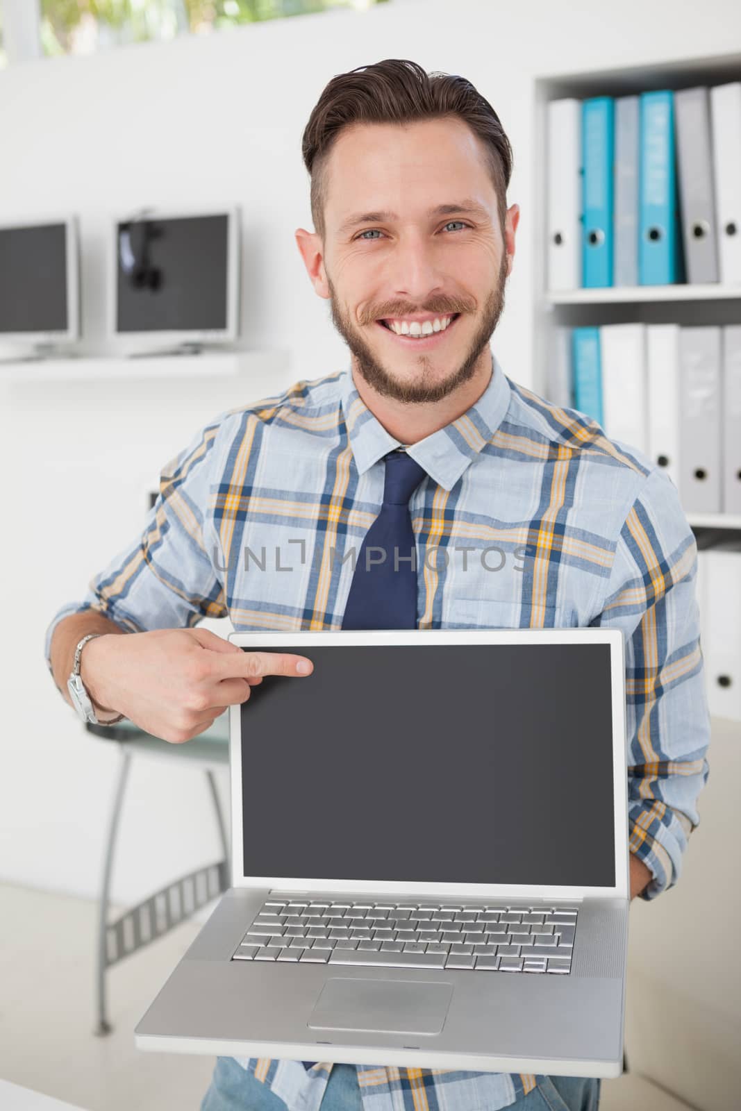 Happy casual businessman pointing to laptop by Wavebreakmedia