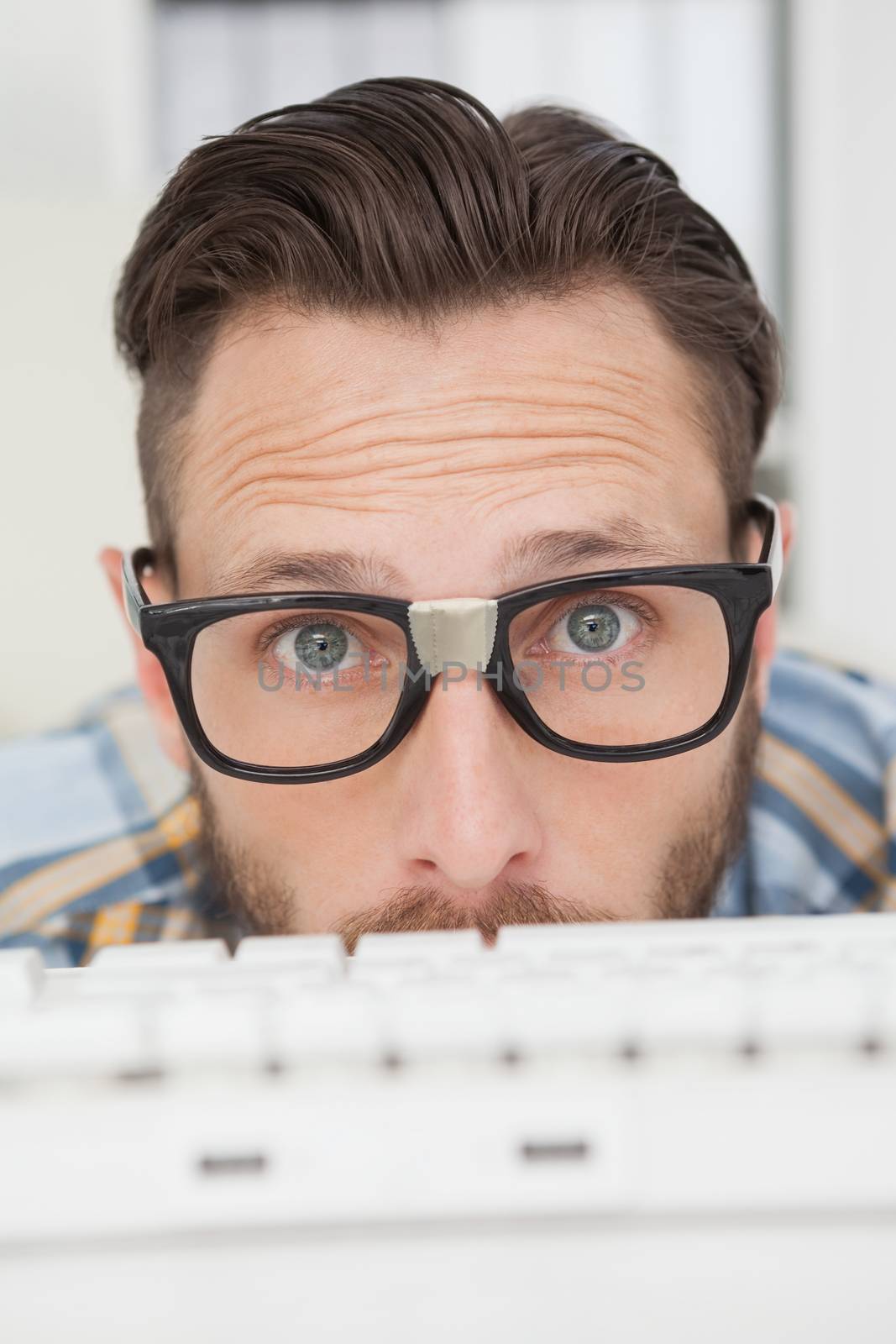 Puzzled nerdy businessman working on computer by Wavebreakmedia