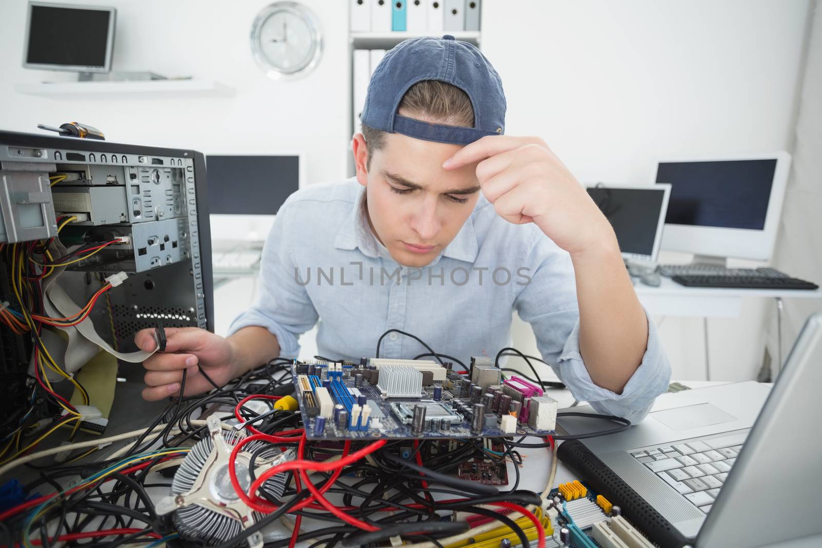 Computer engineer working on broken console with laptop in his office