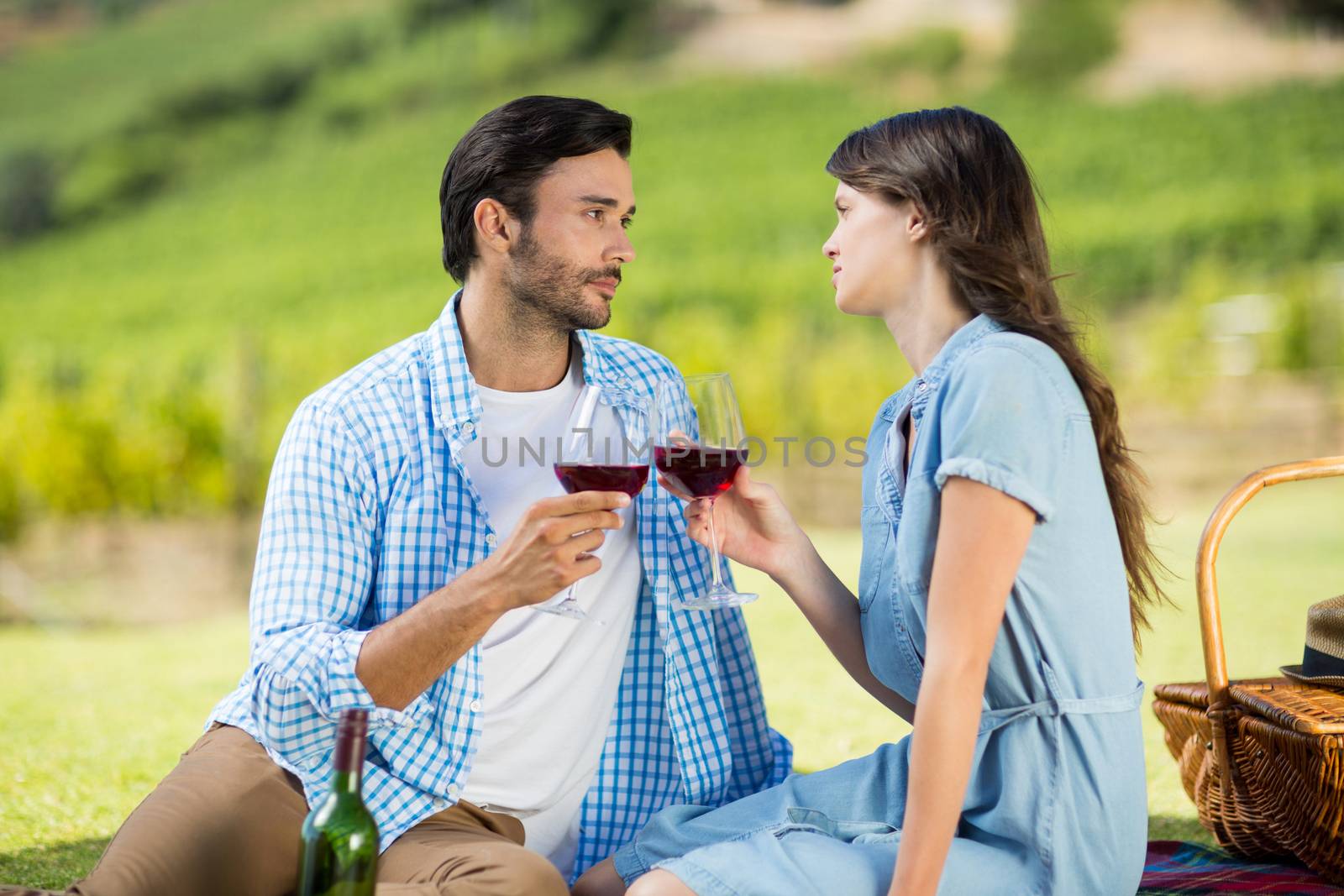 Romantic couple staring at each other while holding wineglasses by Wavebreakmedia