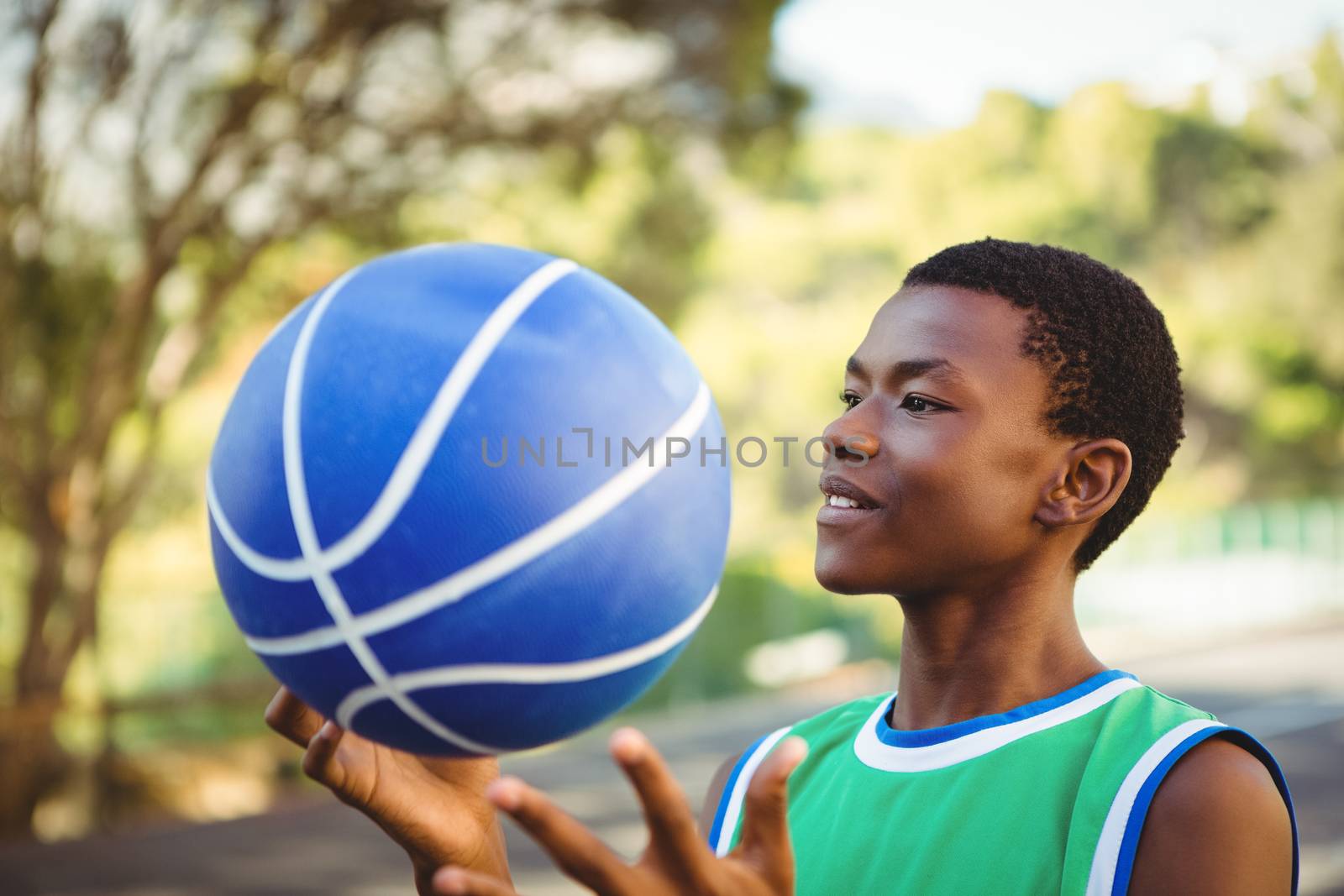 Close up of smiling young man playing with basketball outdoors