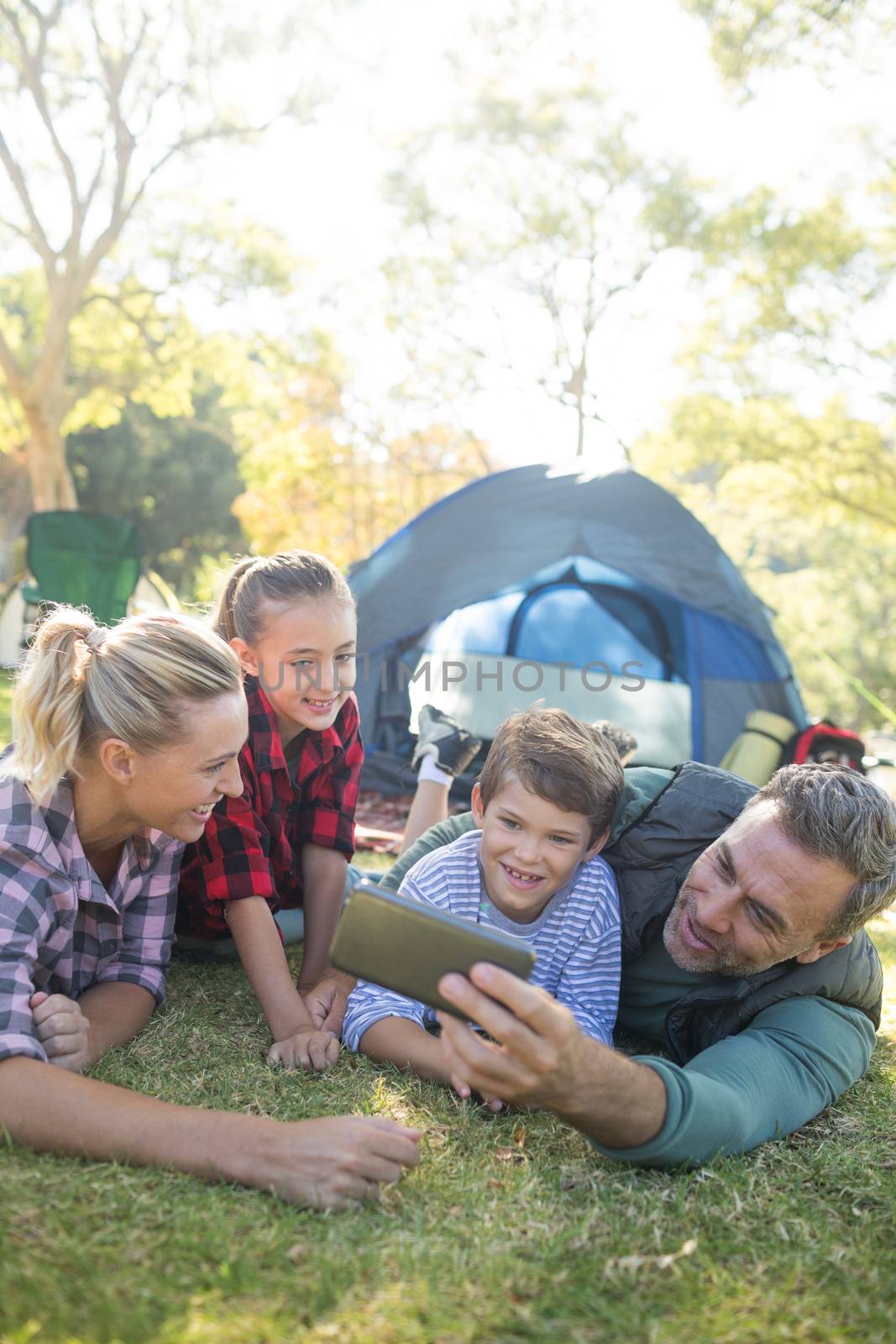 Smiling family taking a selfie outside the tent