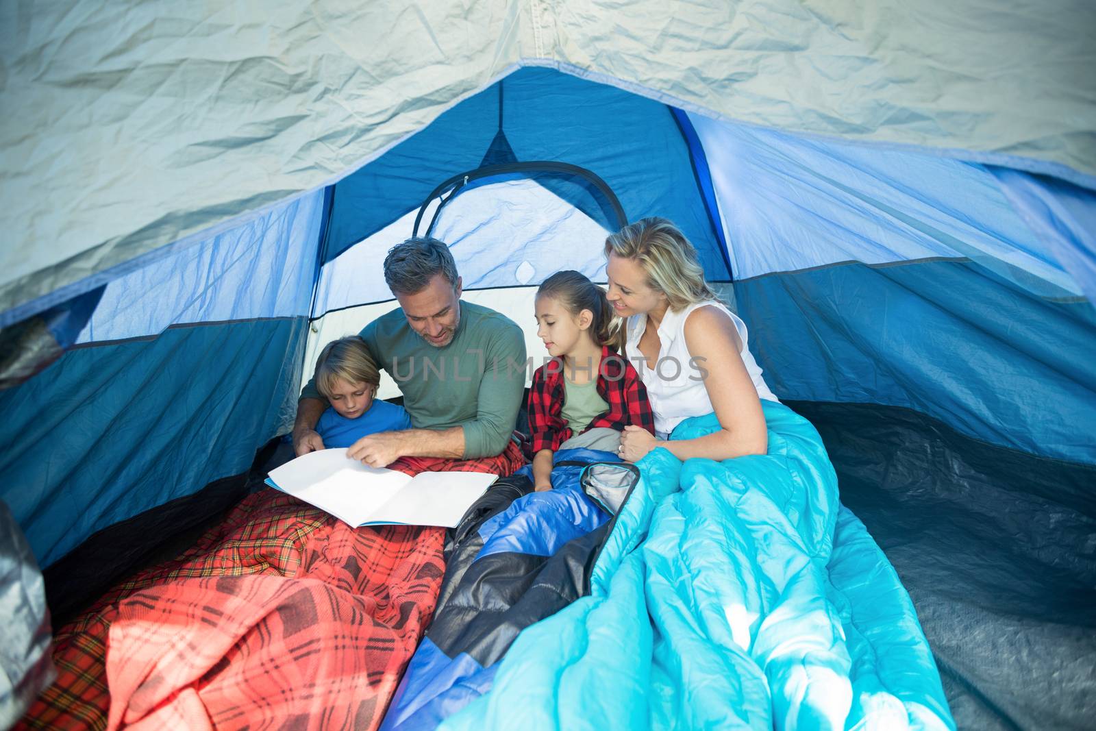 Family reading book together in the tent
