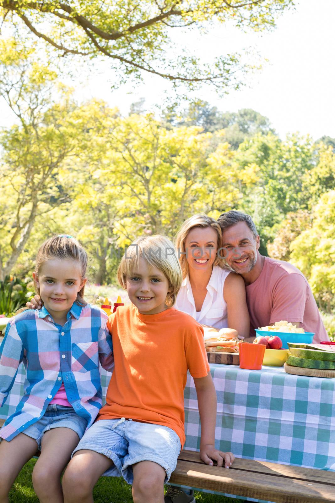 Happy family sitting at table in park by Wavebreakmedia