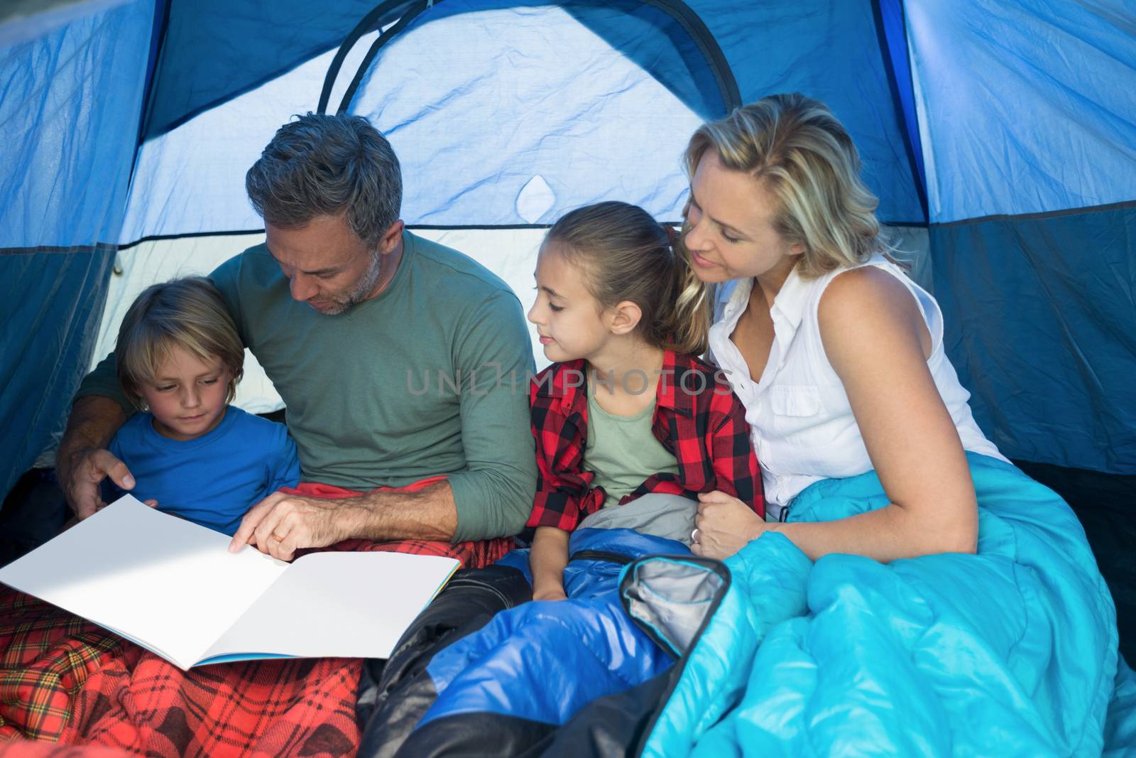 Family reading book together in the tent