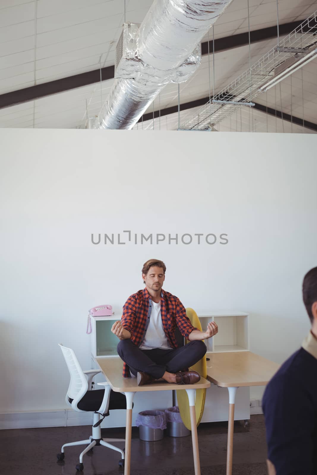 Young businessman doing yoga at office by Wavebreakmedia