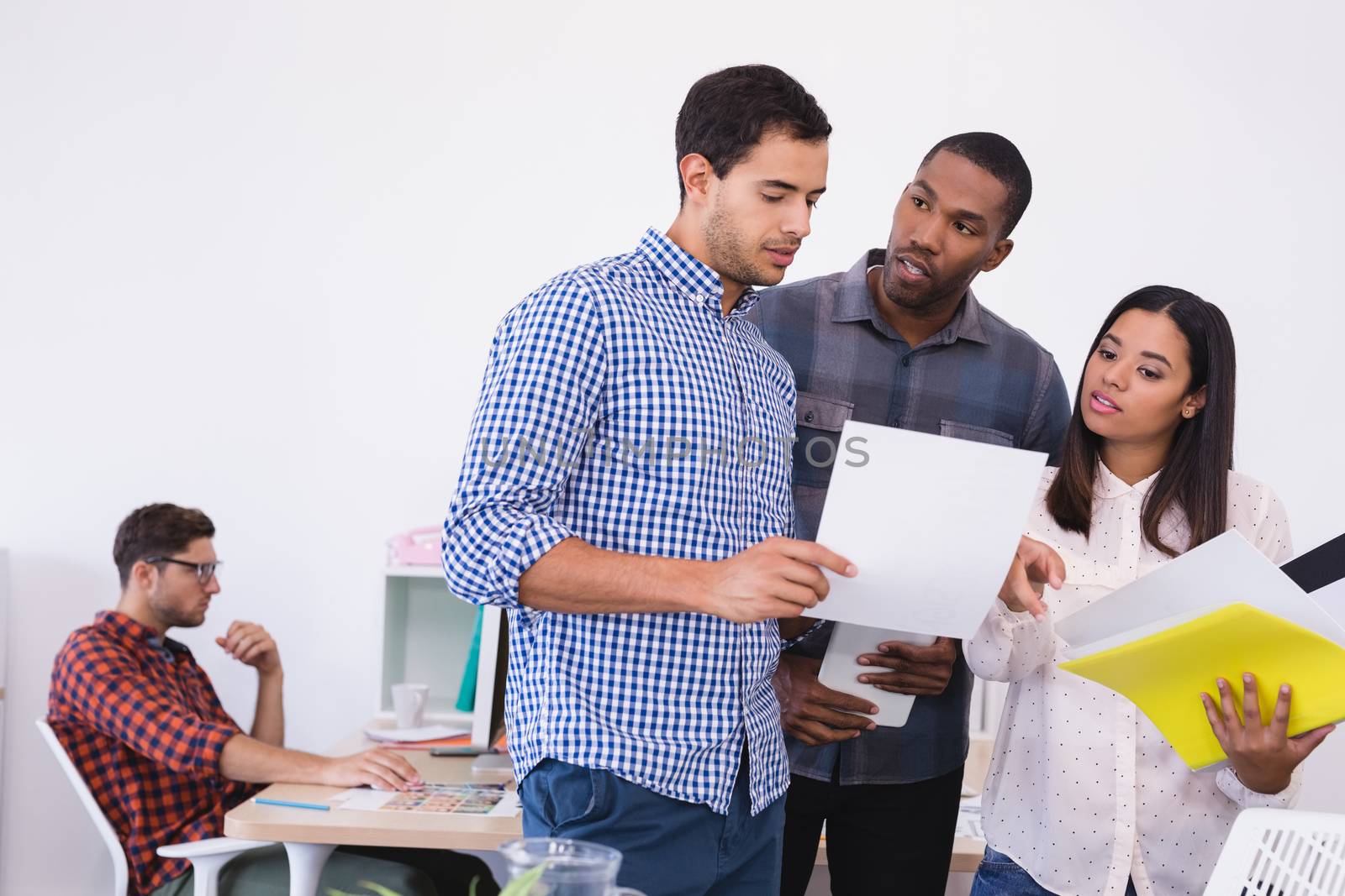 Business people discussing over document while standing in office