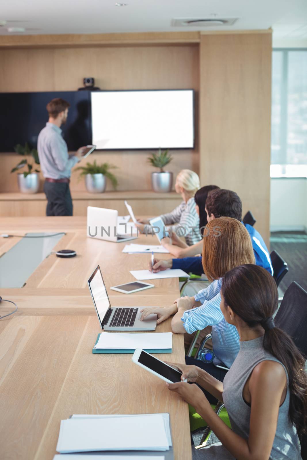 Business people using laptop and digital tablets at conference table during meeting by Wavebreakmedia