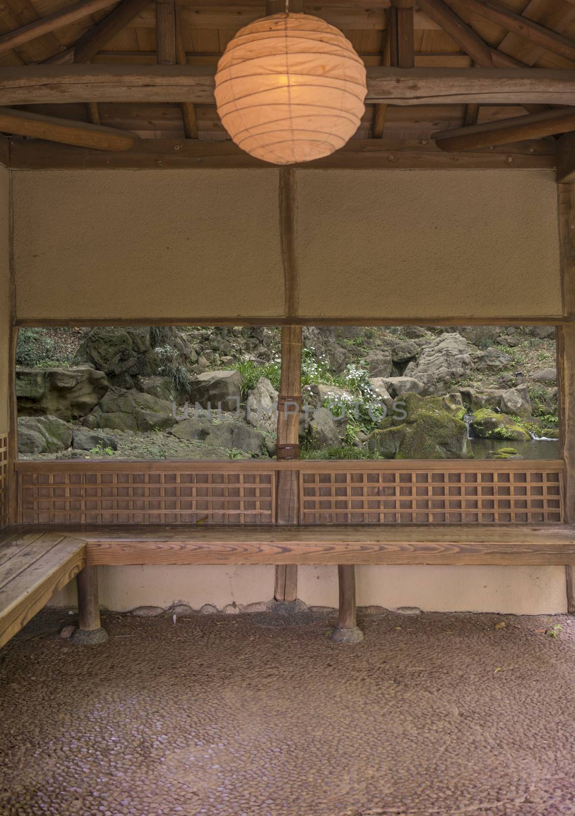 Takimi Japanese tea house lit by a lantern of washi paper overlooking a waterfall and stone islets with moss in the pond of Rikugien park garden in Bunkyo district, north of Tokyo. The park was created at the beginning of the 18th century.