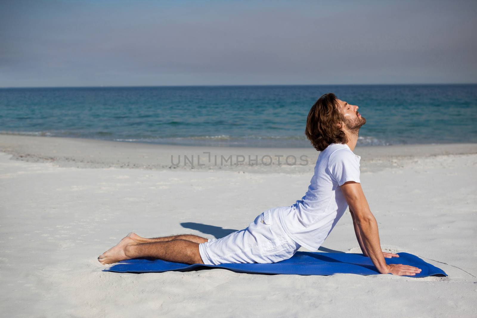 Man performing yoga at beach on a sunny day