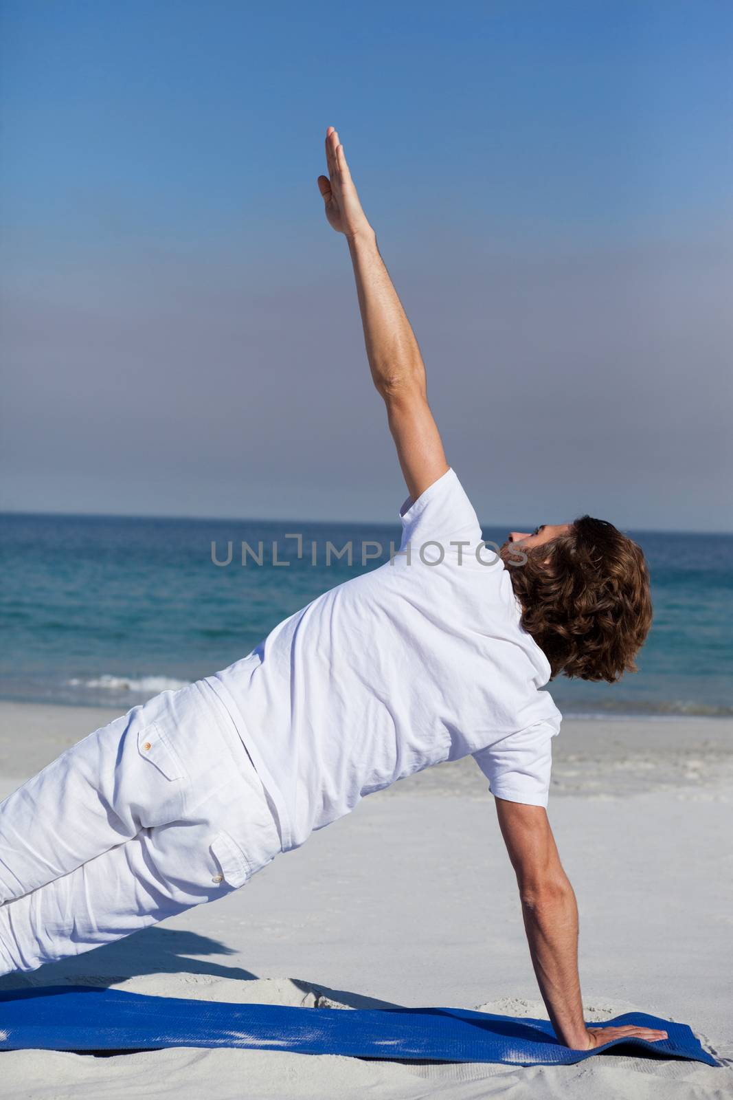 Man performing yoga at beach by Wavebreakmedia