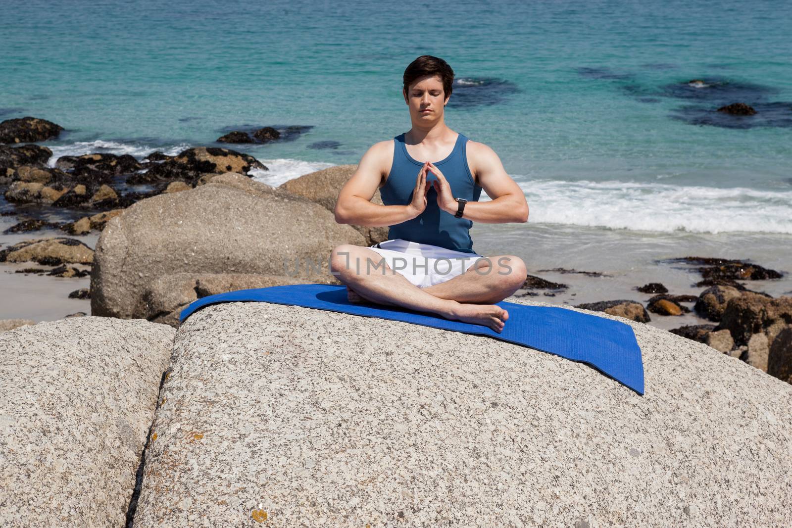 Man performing yoga on rock by Wavebreakmedia