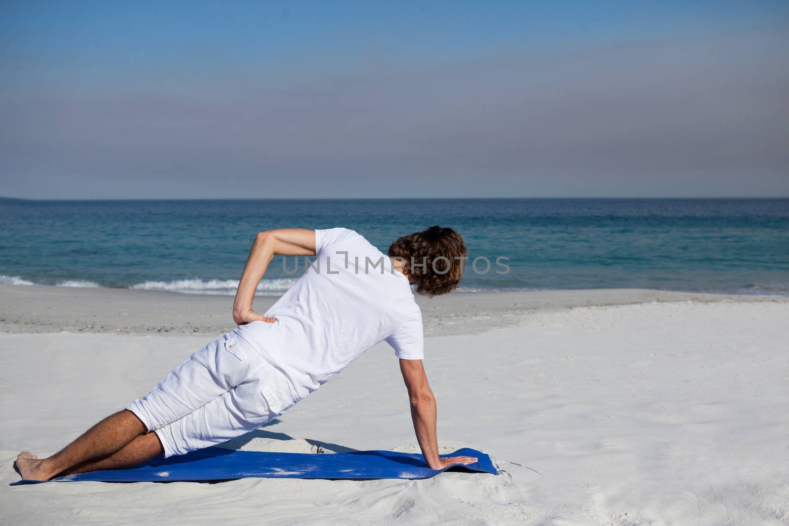 Man performing yoga at beach on a sunny day