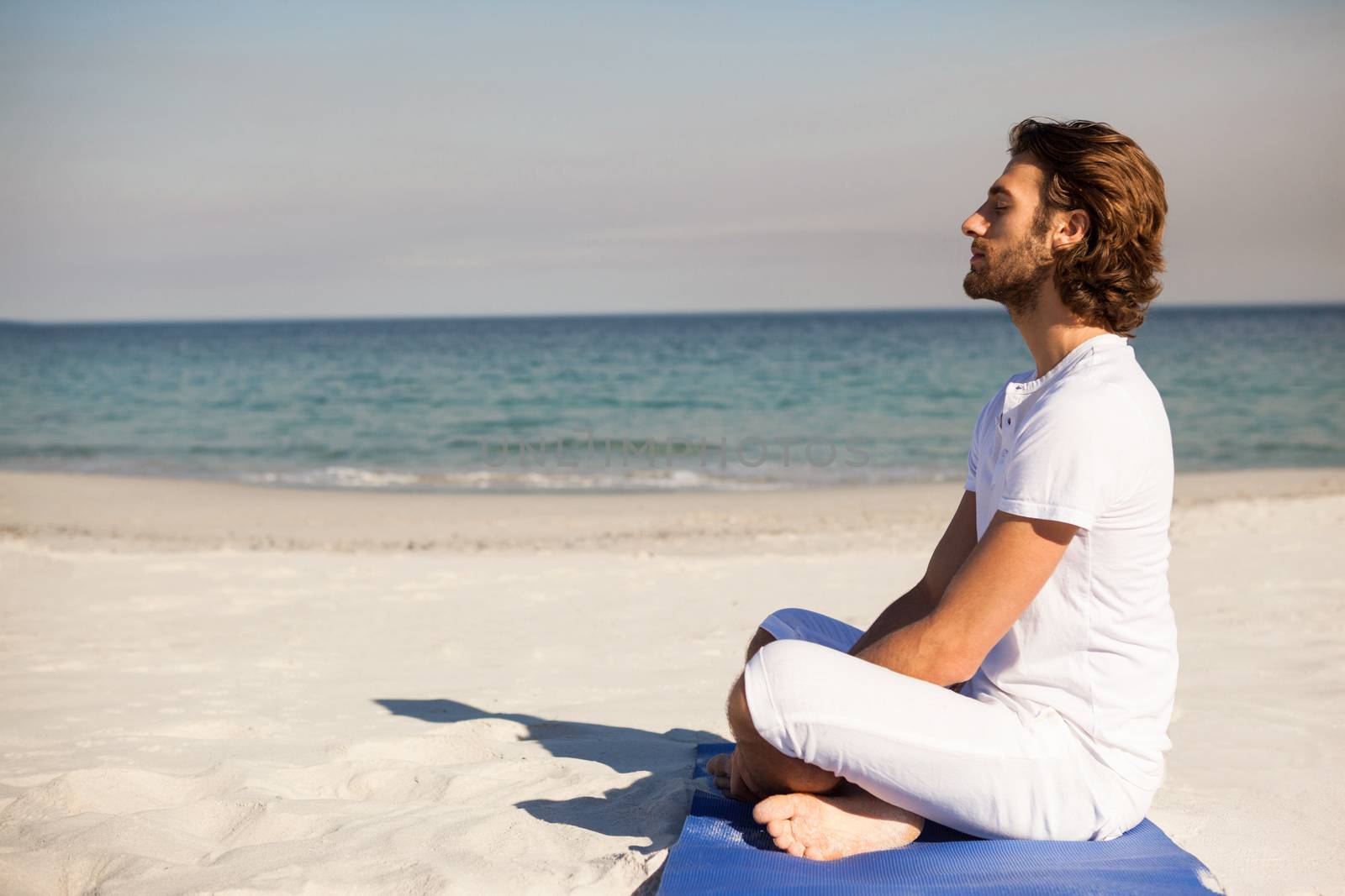 Man performing yoga at beach by Wavebreakmedia