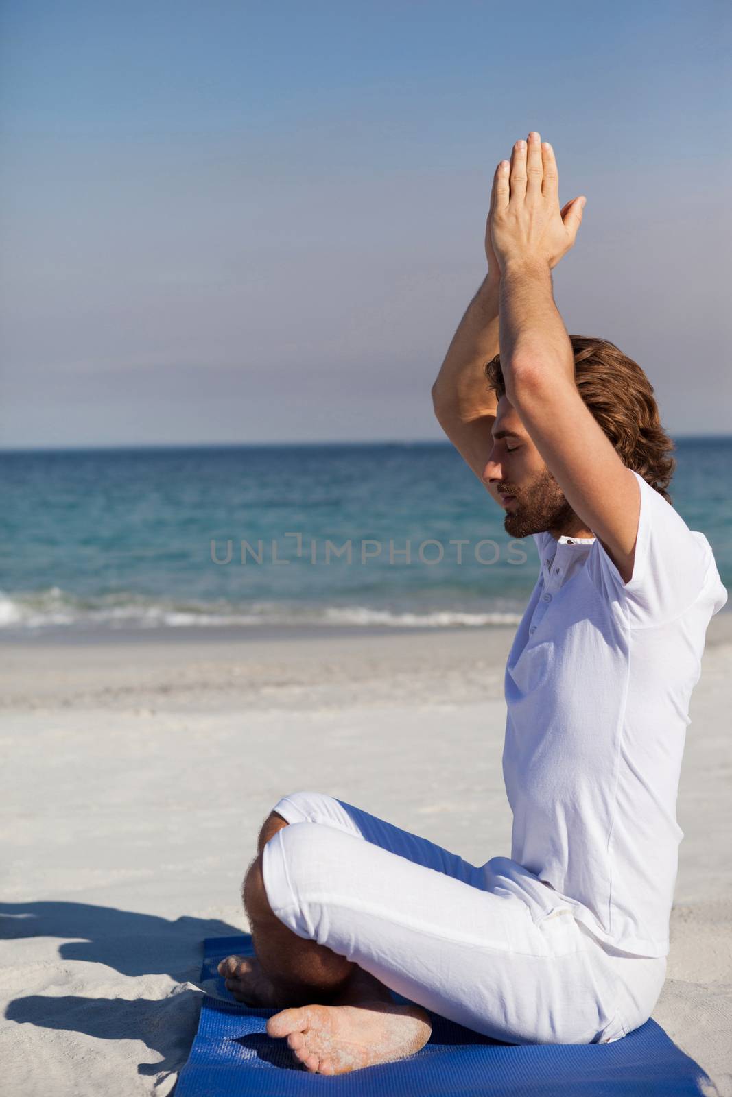 Man performing yoga at beach by Wavebreakmedia