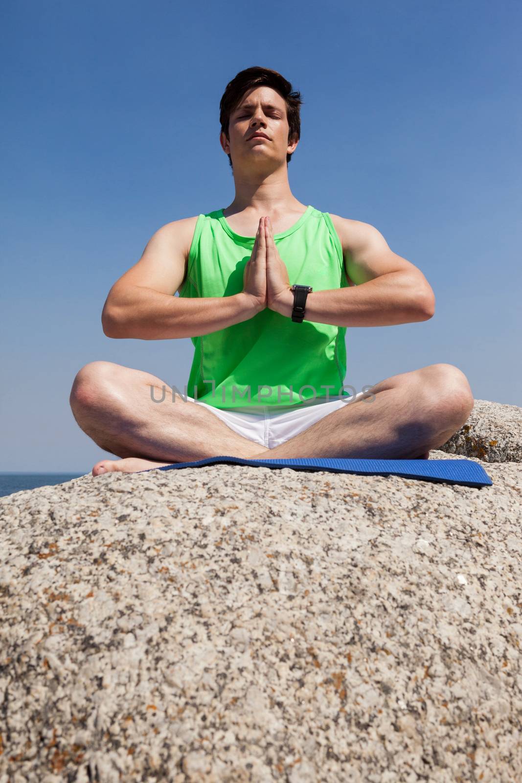 Man performing yoga on rock by Wavebreakmedia