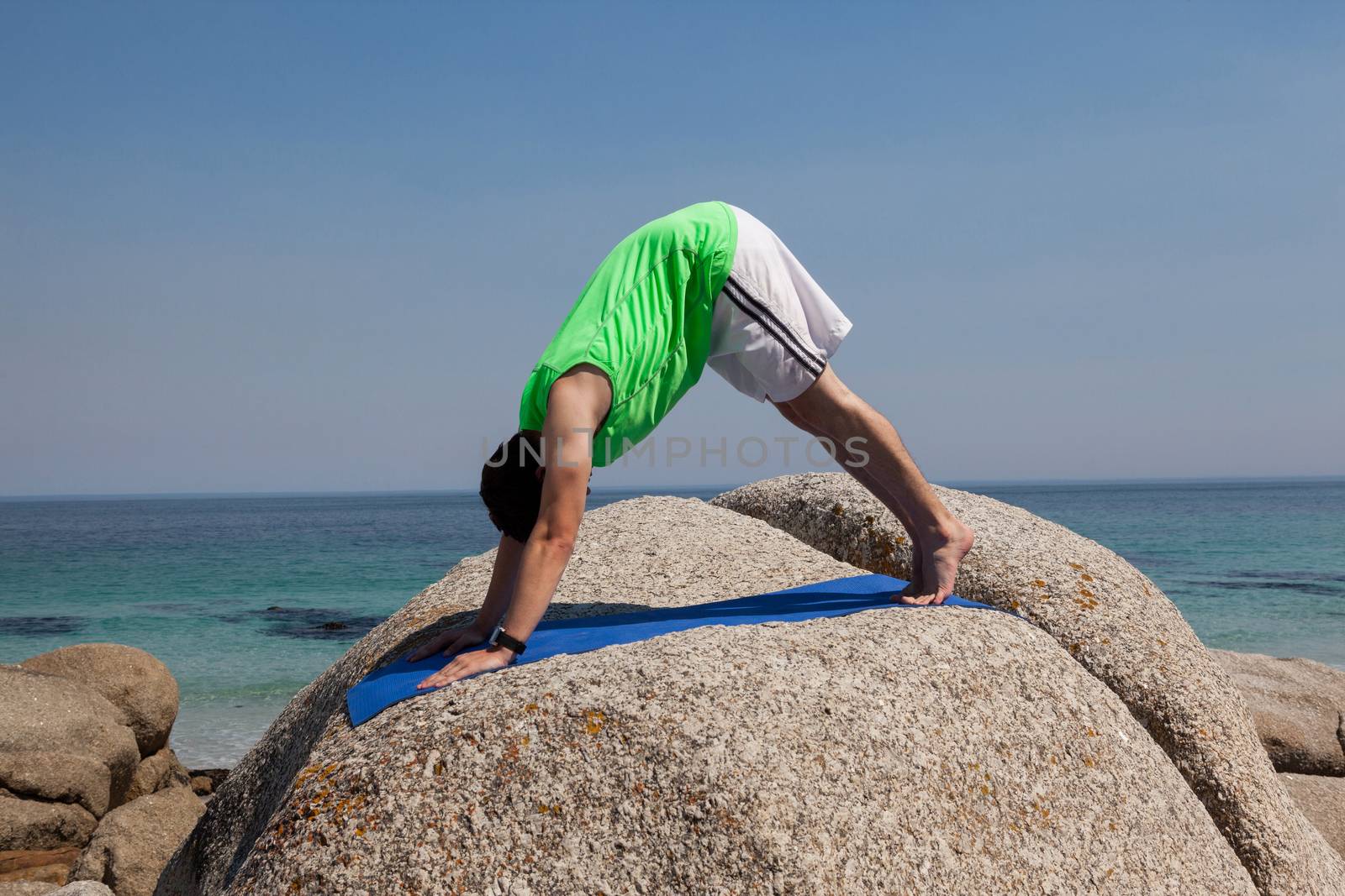 Man performing yoga on rock by Wavebreakmedia