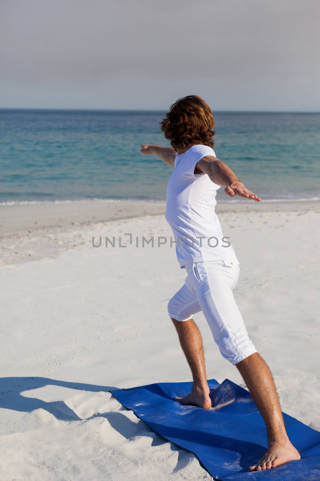 Man performing yoga at beach by Wavebreakmedia