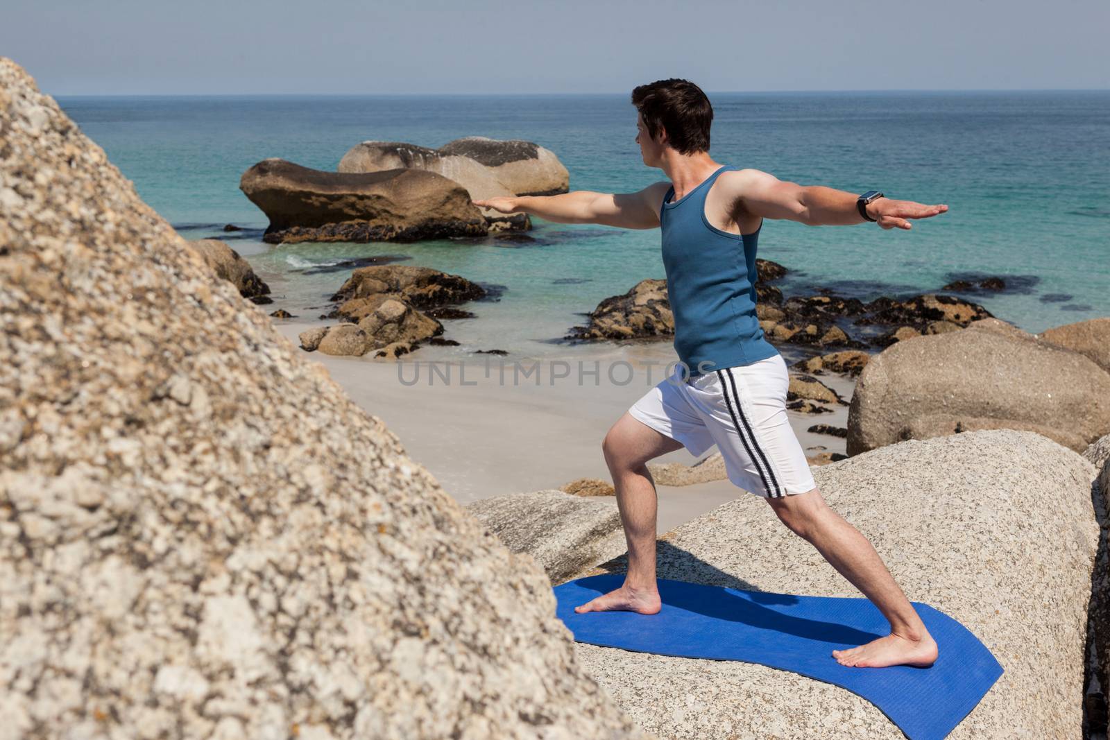 Man performing yoga on rock by Wavebreakmedia